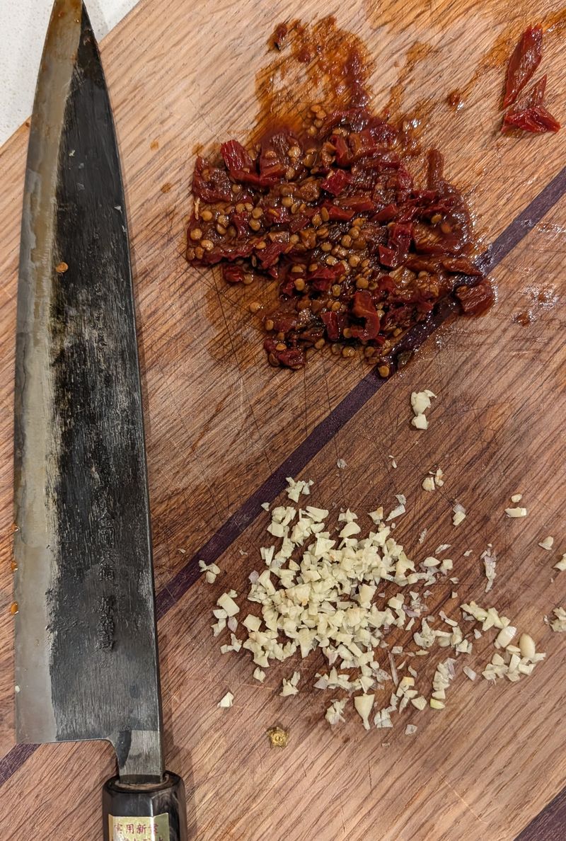 Knife prep with garlic and chipotles on cutting board